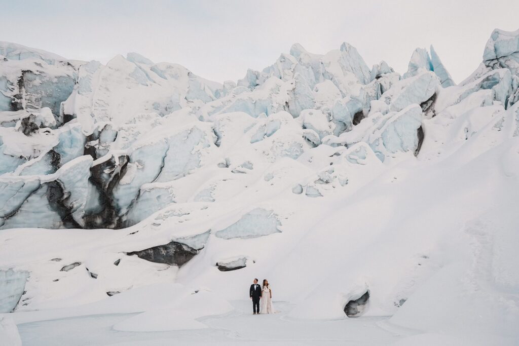 Bride and groom hold hands on a snow Alaska glacier during their adventure elopement photos