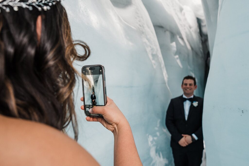 Bride takes a photo of groom in an ice cave in Alaska