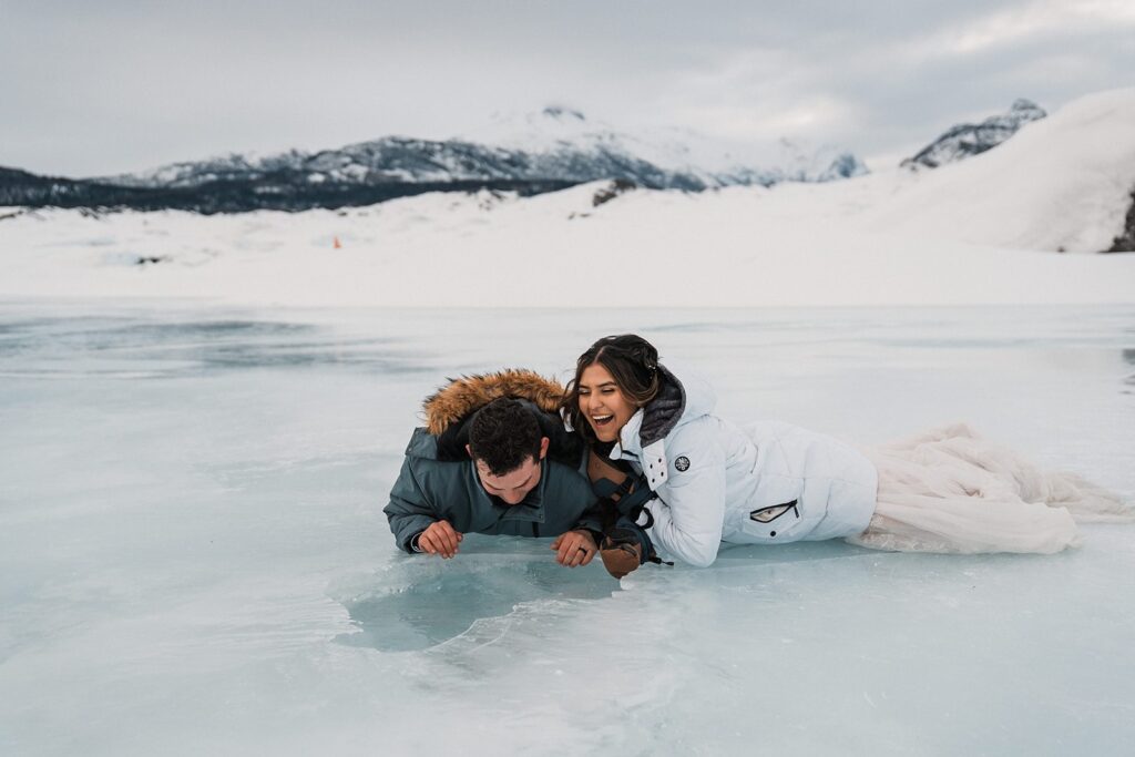 Bride and groom lay on the ground and drink water from a glacier 