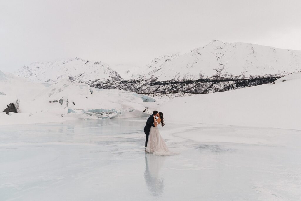 Bride and groom kiss on an icy lake during their glacier elopement in Alaska