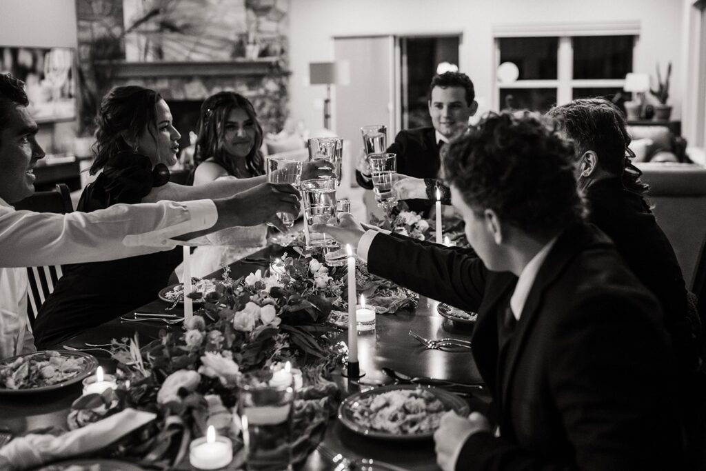 Bride and groom toast with their guests at their private meal at their elopement cabin