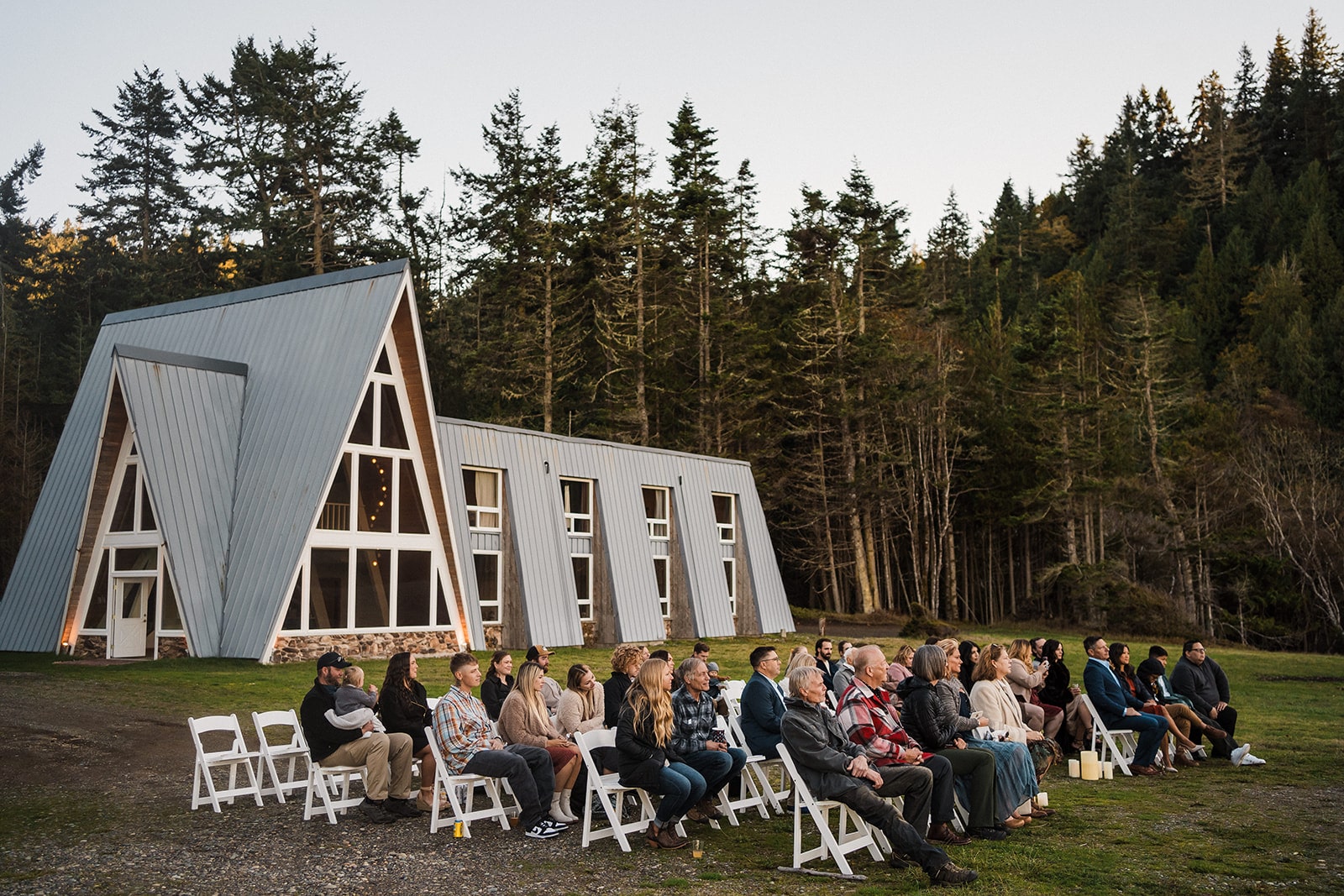 Guests sit on white wood chairs during a micro wedding venue ceremony at Agate Beach Lodge