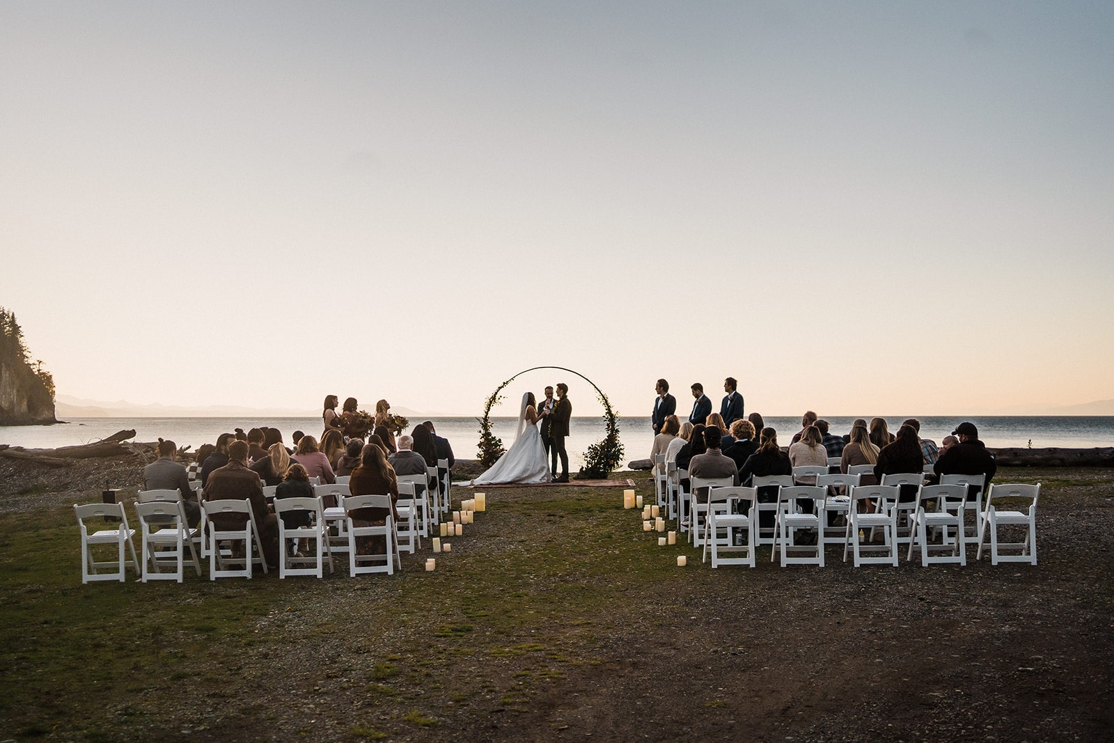 Guests sit on white wood chairs during a micro wedding venue ceremony at Agate Beach Lodge