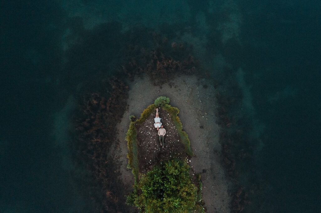 Bride and groom lay on the ground on a grassy peninsula during their Snoqualmie adventure elopement