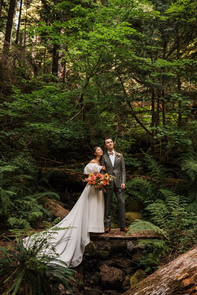 Bride and groom stand on a log during their forest adventure elopement 