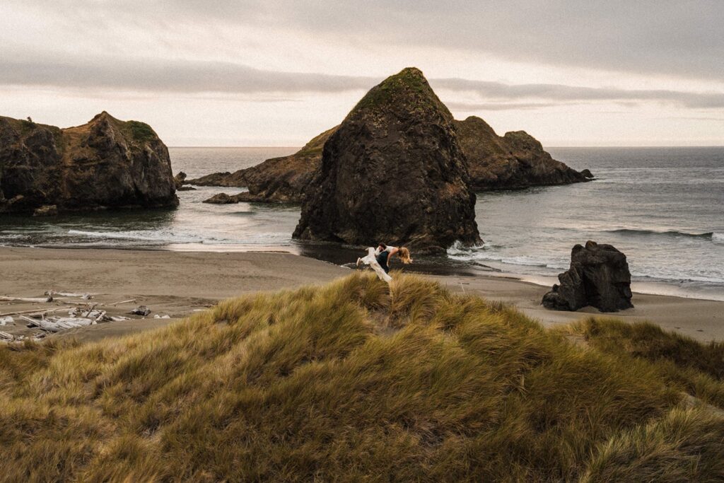 Groom lifts bride and spins her around during their adventure elopement on the Oregon Coast