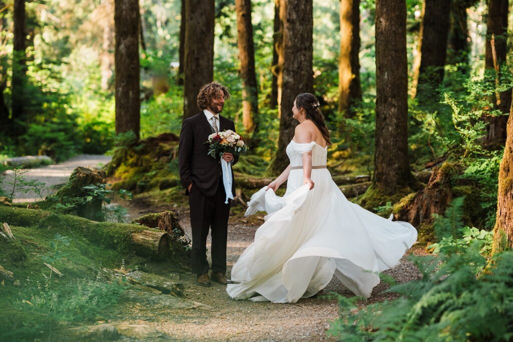 Bride twirls in her wedding dress on a forest trail