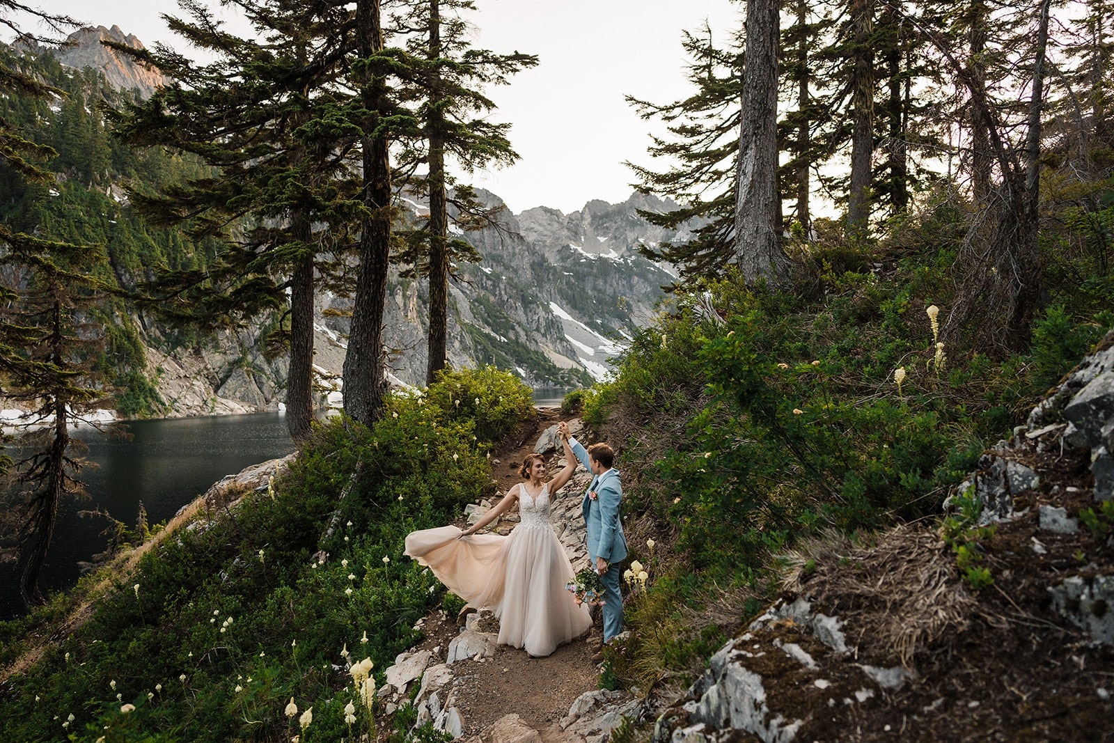 Groom twirls bride on a mountain trail during their Washington adventure elopement