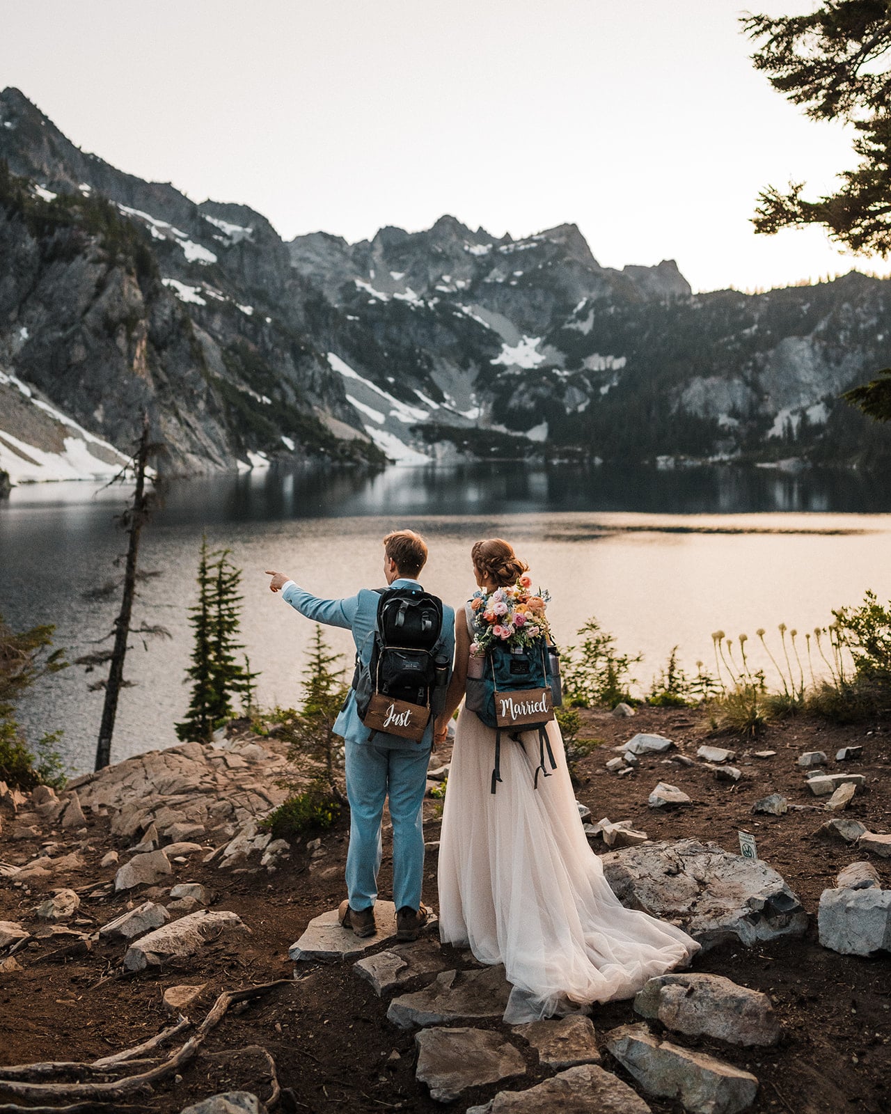 Bride and groom wear hiking backpacks during their adventure elopement in the mountains 