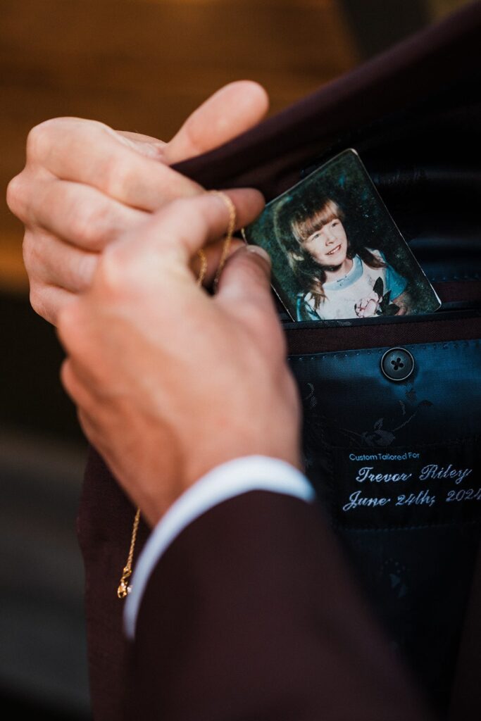 Groom pulls an old photo of out his suit jacket pocket during his intimate cabin wedding in Washington