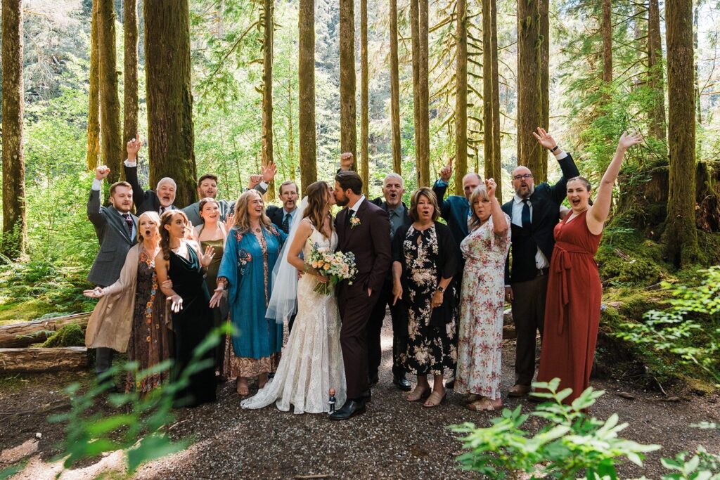 Bride and groom kiss while guests cheer at their intimate cabin wedding in Washington