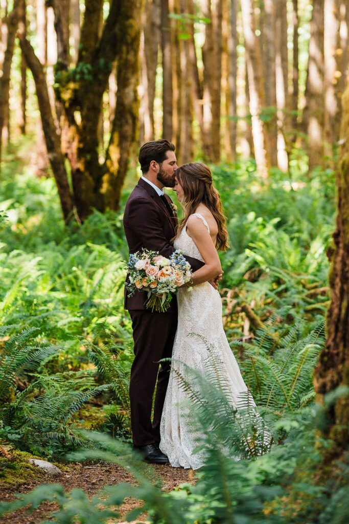 Groom kisses bride on the forehead during their forest elopement photos in Snoqulamie Valley