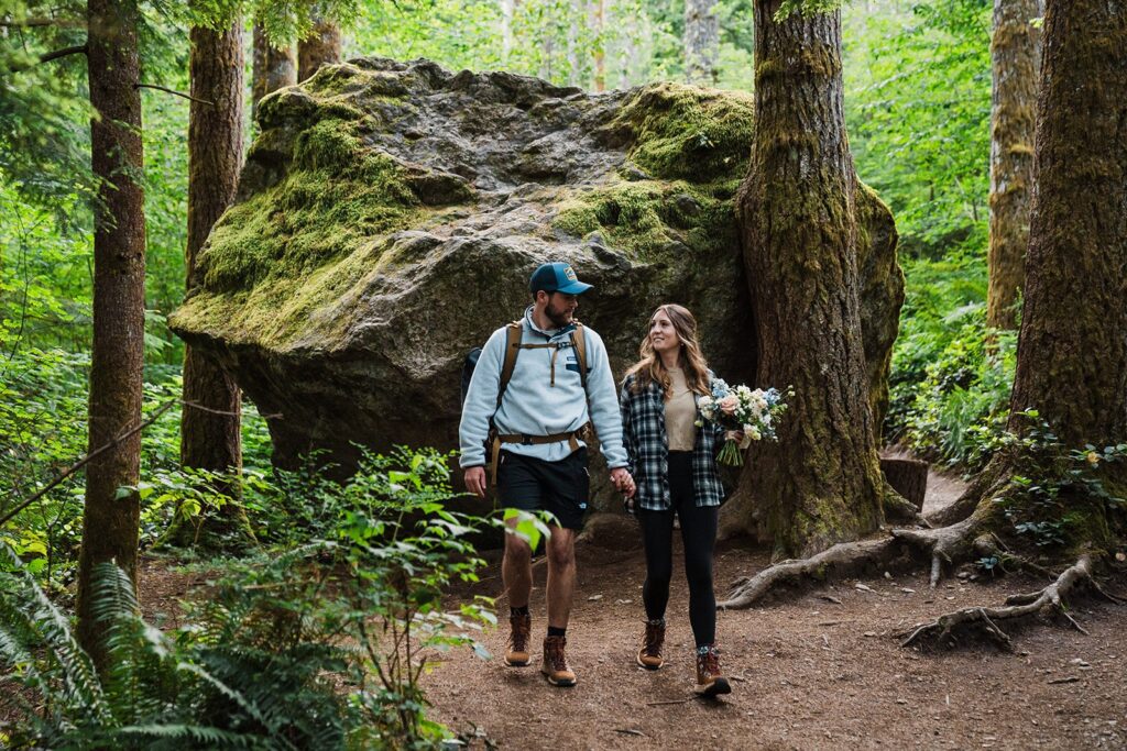 Bride and groom hold hands as they walk through the forest during their intimate cabin wedding in Snoqualmie Valley