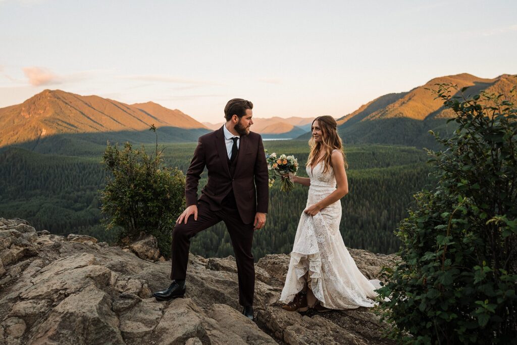 Bride and groom walk across a mountain trail during their Snoqualmie Valley wedding hike