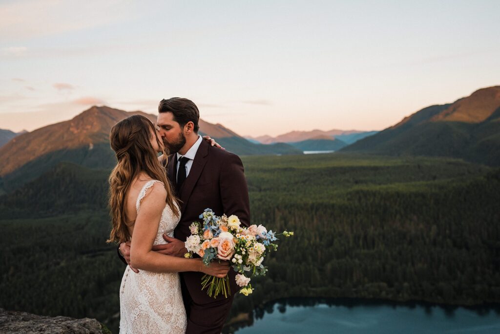 Bride and groom kiss on the top of a mountain trail during their Snoqualmie Valley wedding 