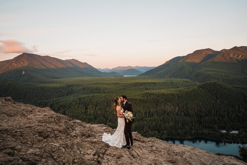 Bride and groom kiss on the top of a mountain trail during their Snoqualmie Valley wedding 