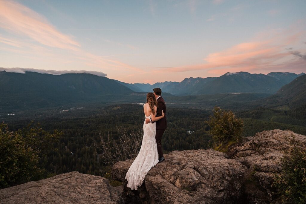 Bride and groom hug as they look out over Snoqualmie Valley during their sunset elopement