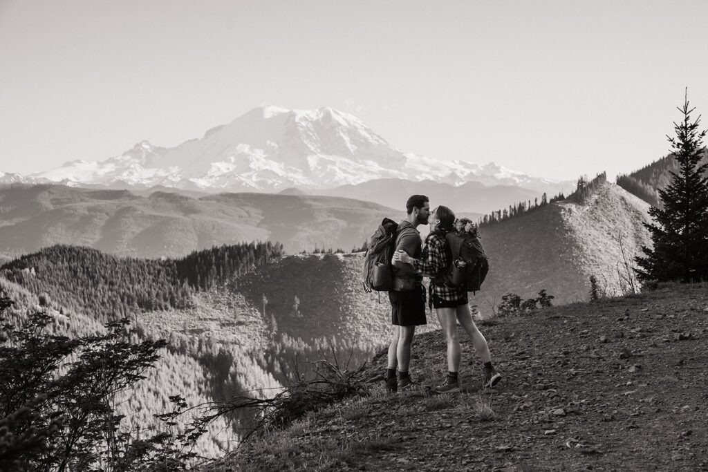 Bride and groom kiss on a mountain trail near Mount Rainier