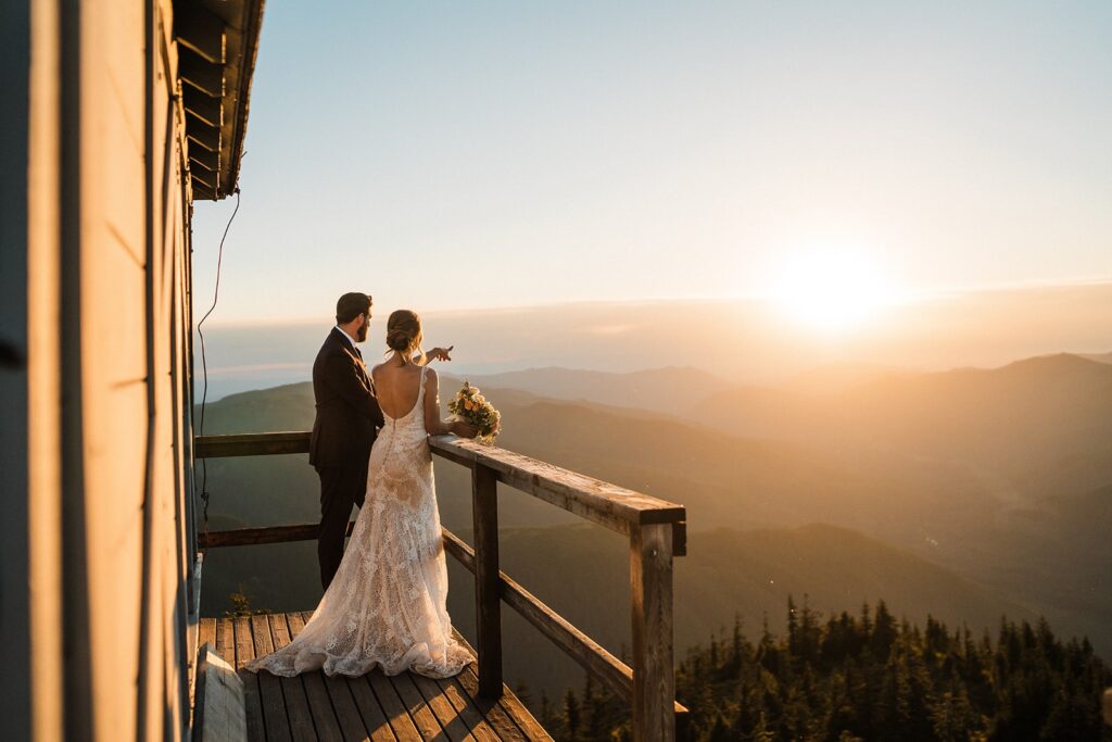 Bride and groom stand on the deck of a fire lookout near Mount Rainier National Park