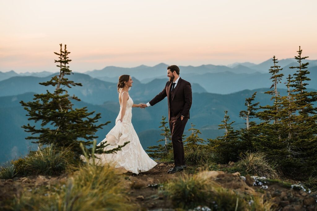 Bride and groom dance on a mountain trail during sunset 