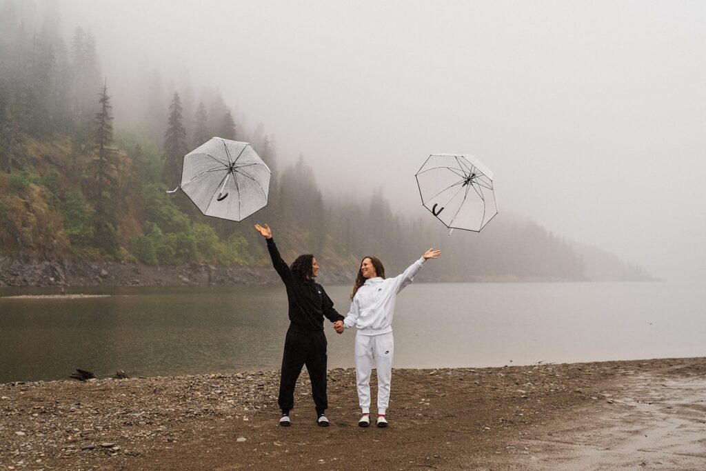 Women throw clear umbrellas into their air during their sunrise session at an alpine lake in Washington