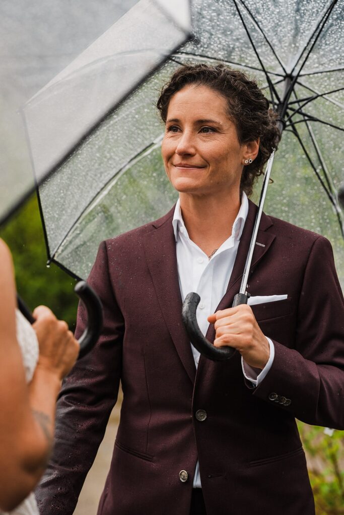 Bride smiles while holding a clear umbrella during her rainy wedding ceremony in Washington