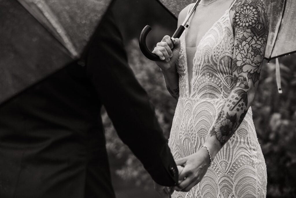 Brides hold hands during their rainy wedding ceremony by an alpine lake in Snoqualmie, WA