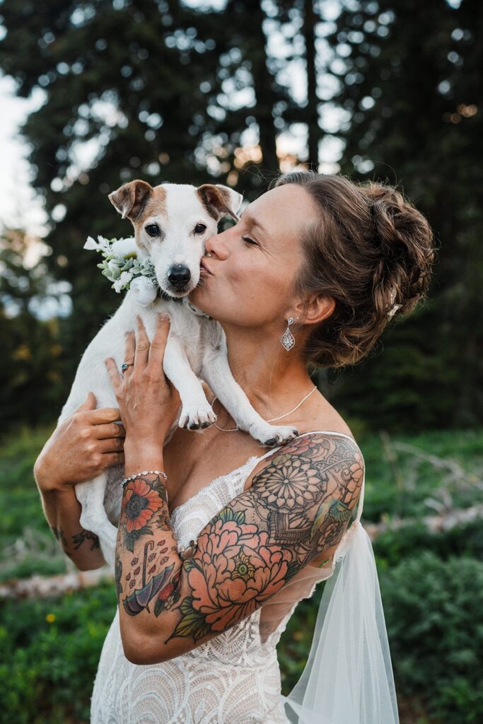 Bride kisses her white and brow dog at her LGBTQ elopement in Washington. 