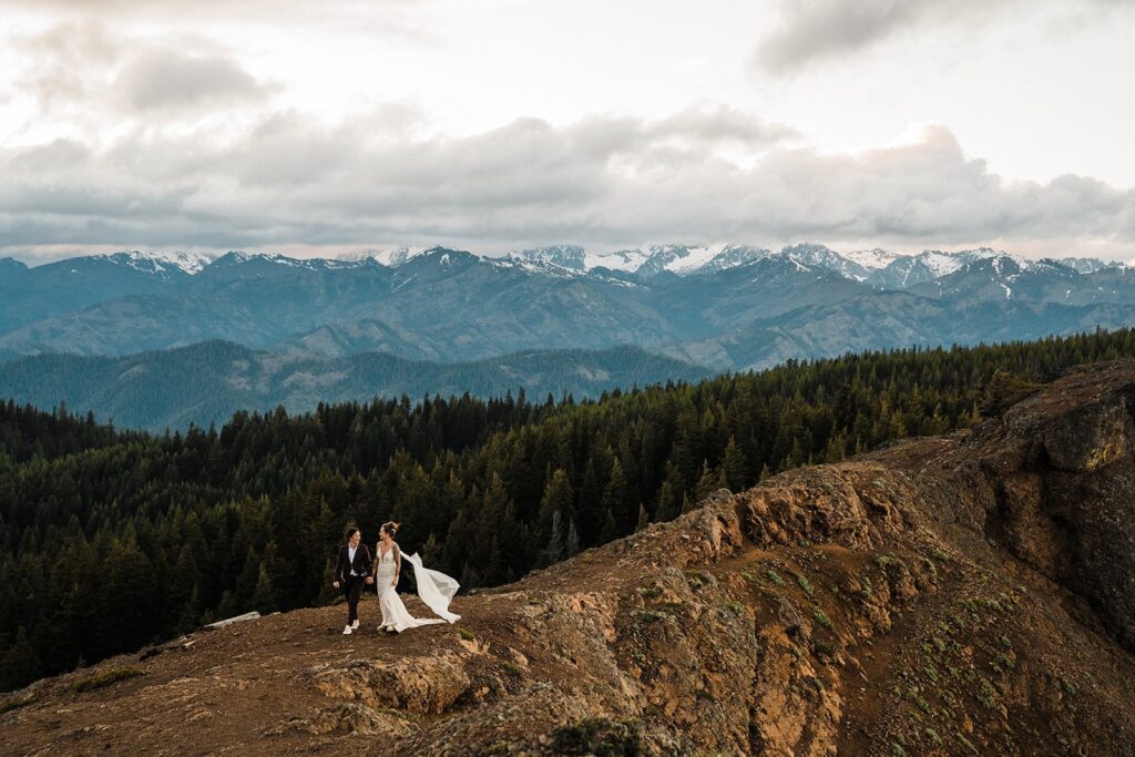 Brides hold hands while walking across the mountains at their LGBTQ Snoqualmie elopement