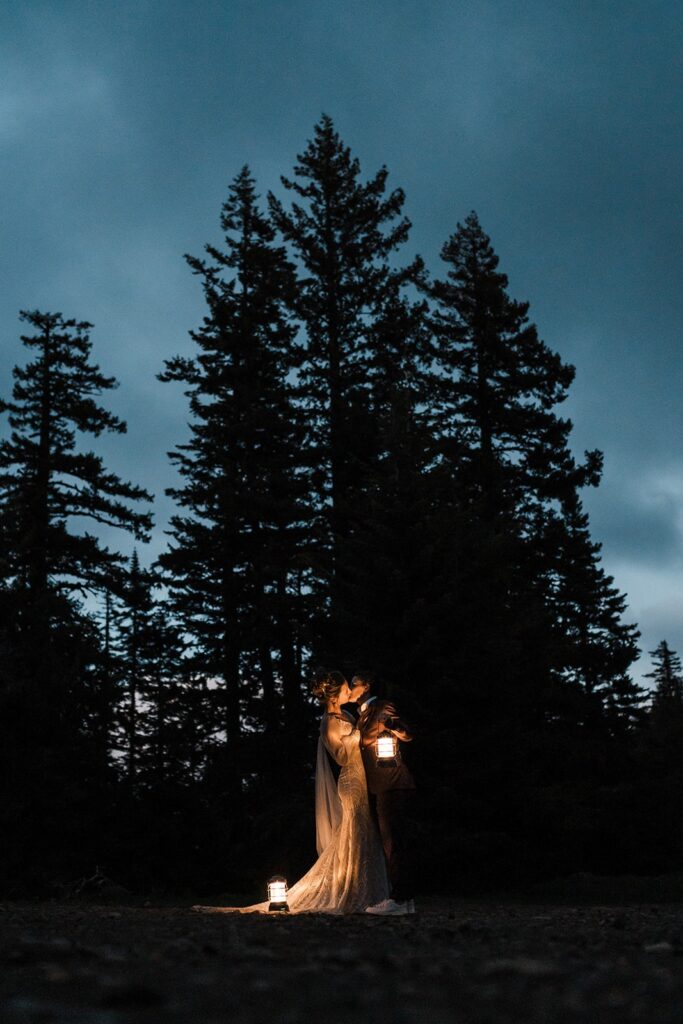 Brides hold lanterns and kiss during blue hour at their Washington wedding during pride month