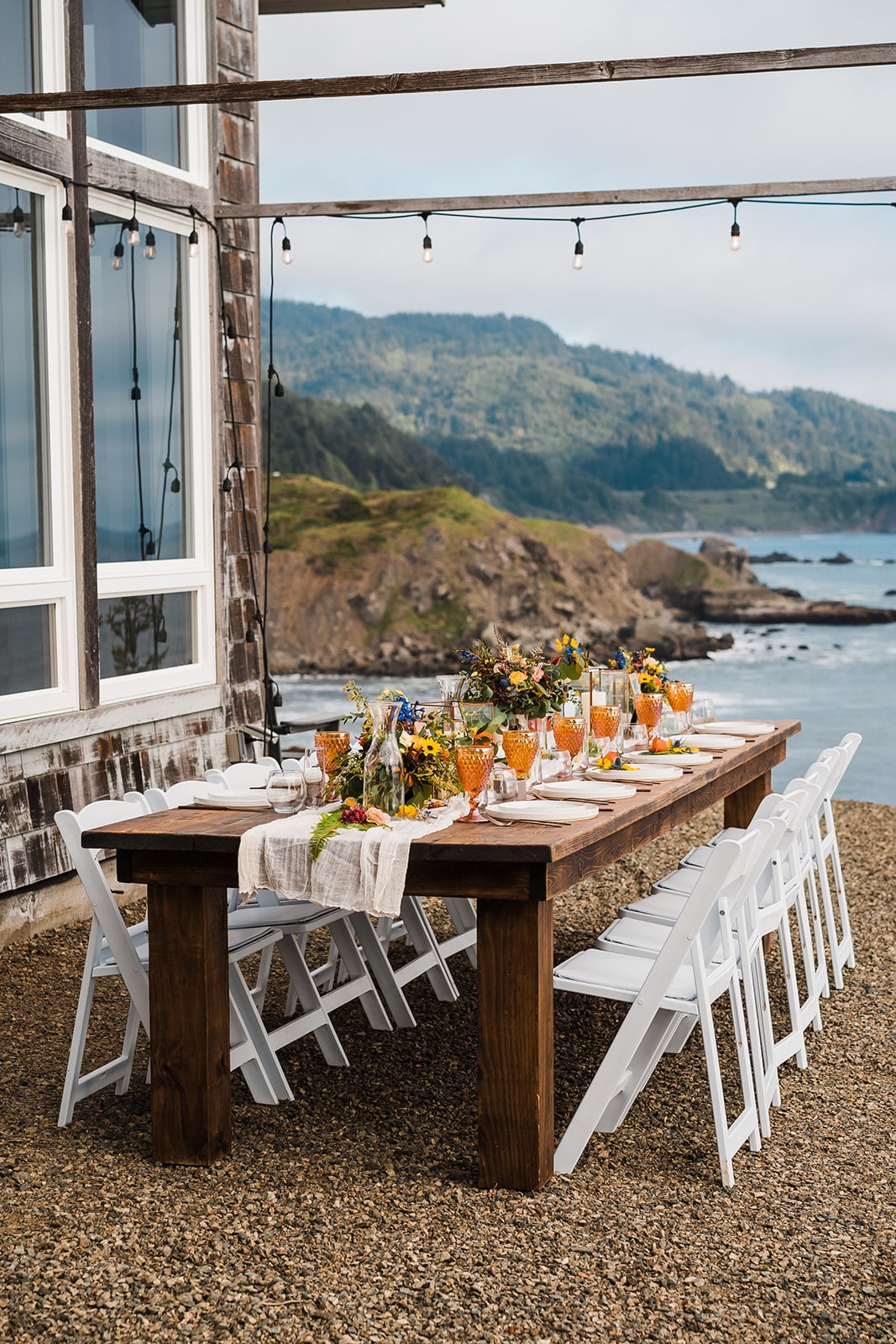 Orange and white flowers decorate an outdoor wood reception table at Crook Point, a micro wedding venue in Oregon