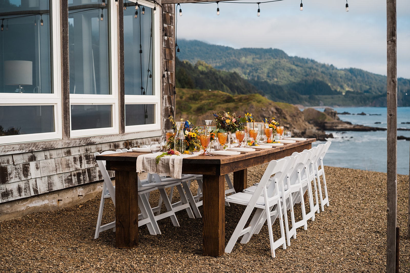 Orange and white flowers decorate an outdoor wood reception table at Crook Point, a micro wedding venue in Oregon