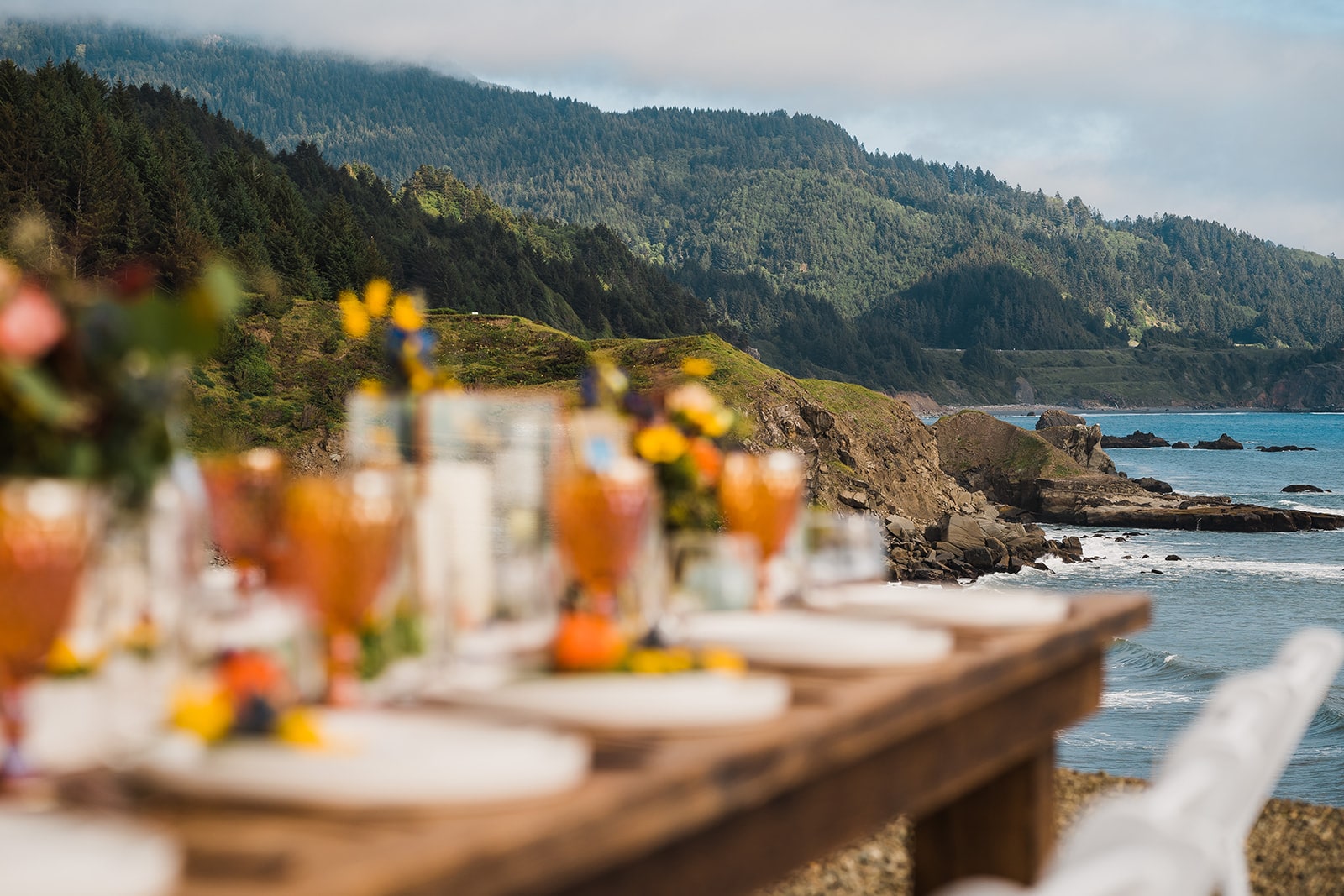 Orange and white flowers decorate an outdoor wood reception table at Crook Point, a micro wedding venue in Oregon