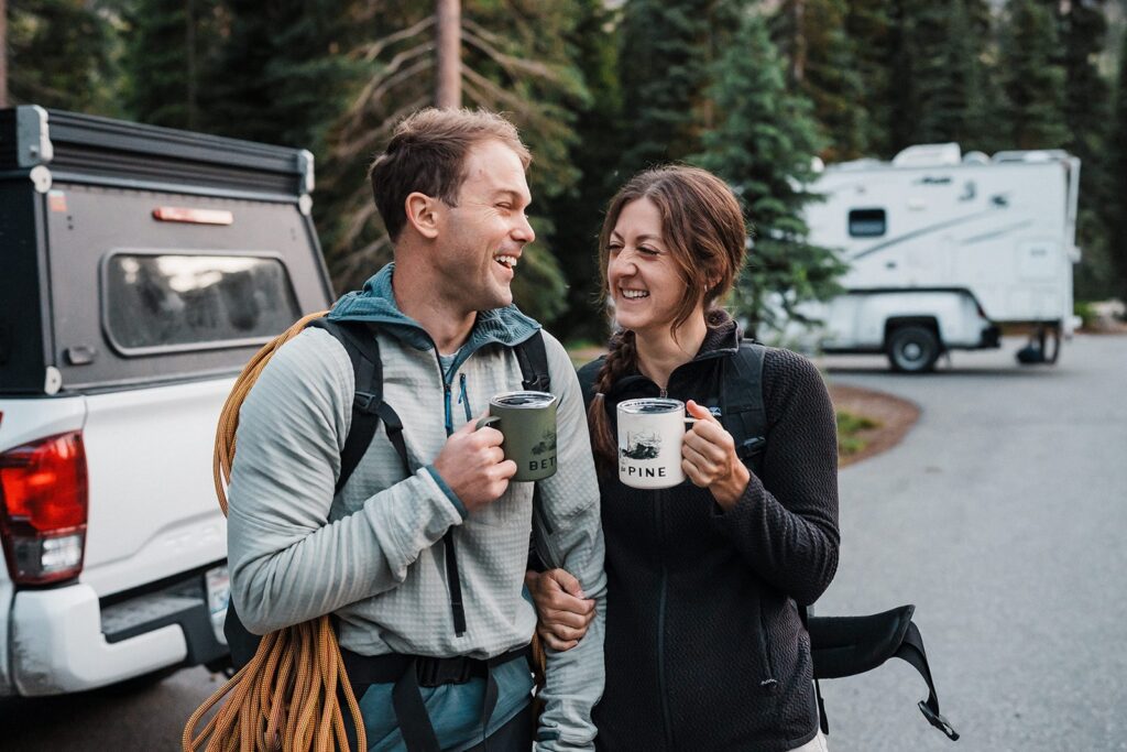 Couple holds white and green coffee mugs while getting ready for their rock climbing elopement in the North Cascades