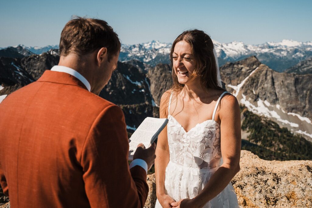 Groom reads private vows and bride laughs during their rock climbing elopement in the North Cascades