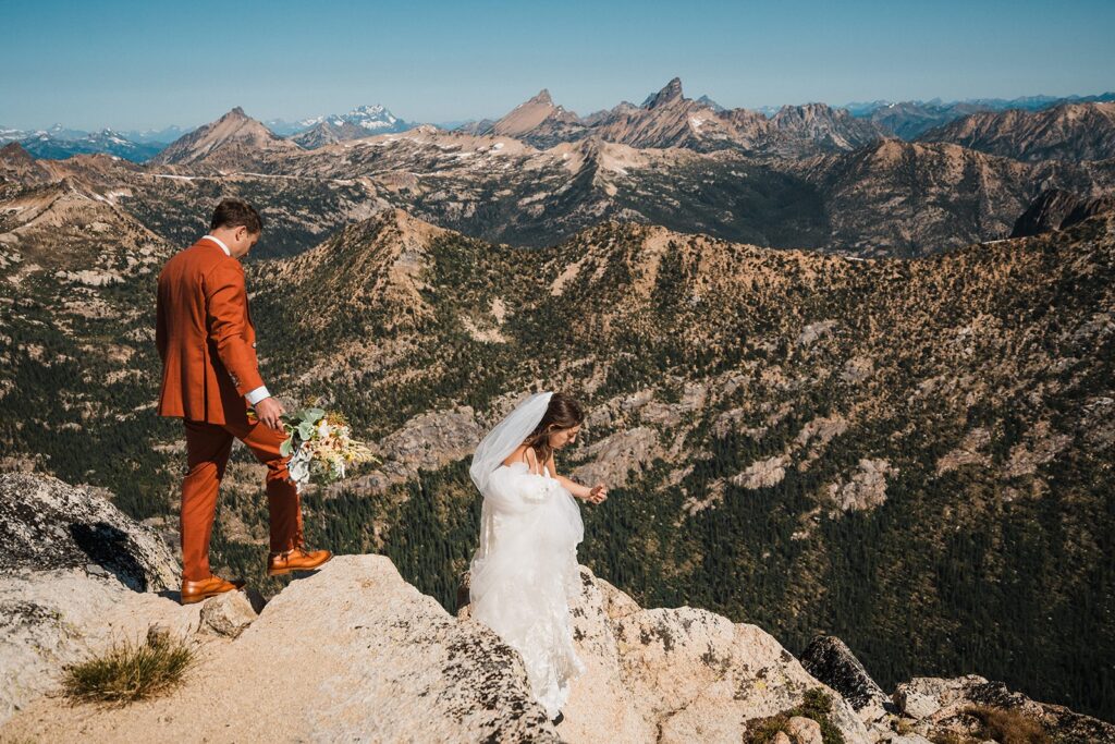 Bride and groom climb down a mountain trail during their North Cascades rock climbing elopement