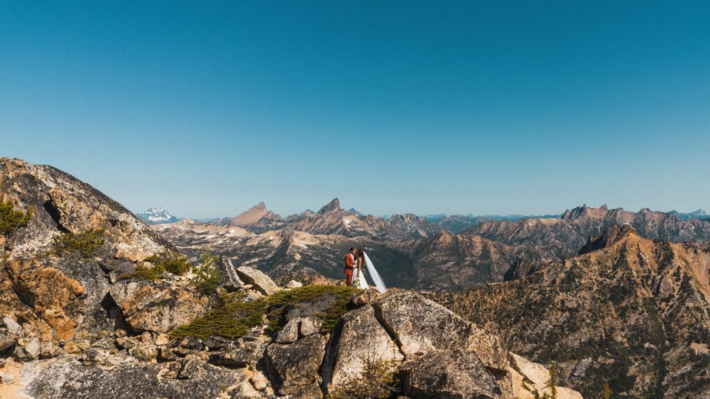 Bride and groom stand on a mountain trail in the North Cascades during their rock climbing elopement