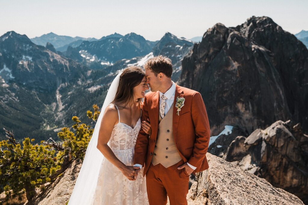 Bride and groom hold hands while standing forehead to forehead during their North Cascades National Park elopement