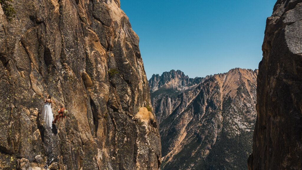 Bride and groom climb a mountain wall during their rock climbing elopement in the North Cascades