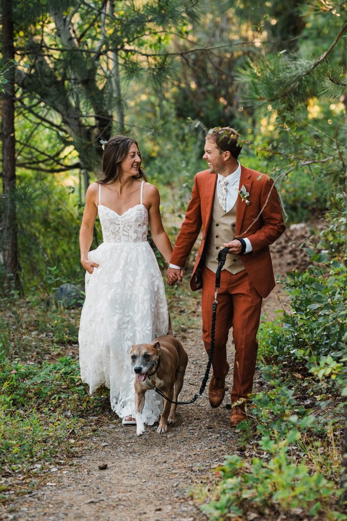 Bride and groom walk their dog through a forest trail during their elopement in North Cascades National Park