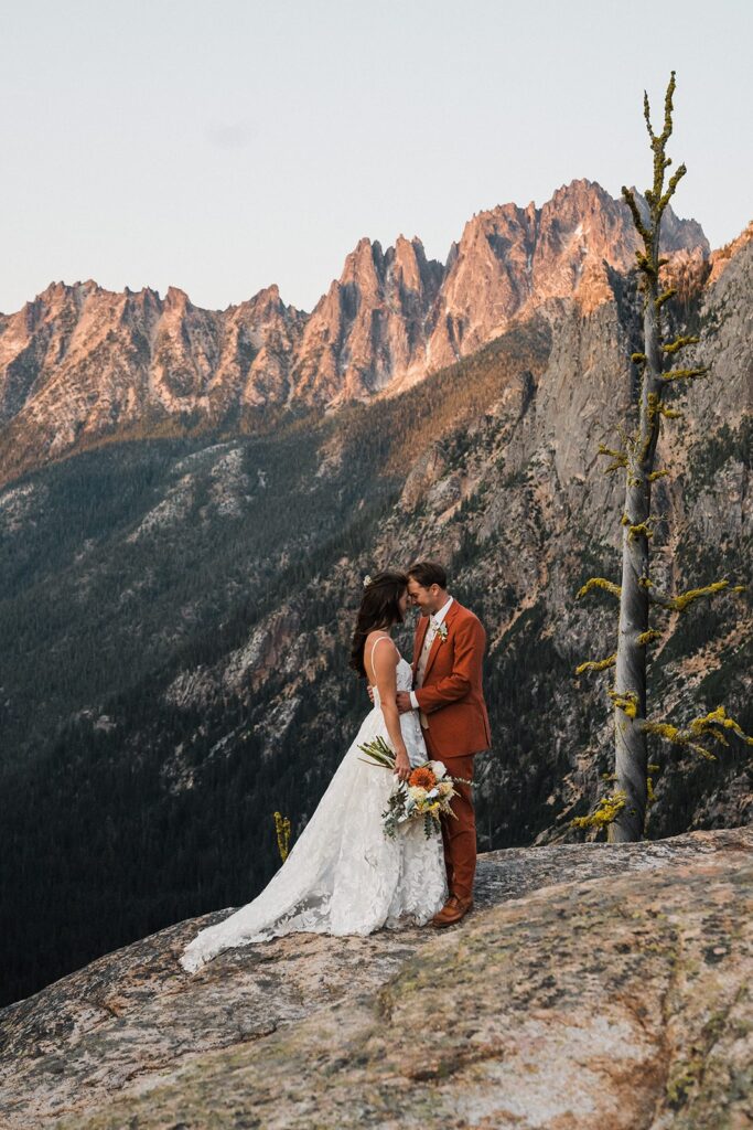 Bride and groom stand forehead to forehead on a mountain trail after their rock climbing elopement