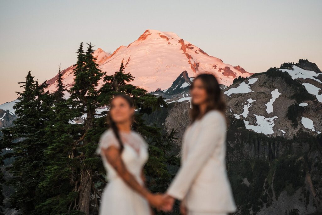 Brides hold hands during their summer sunrise elopement at Artist Point 