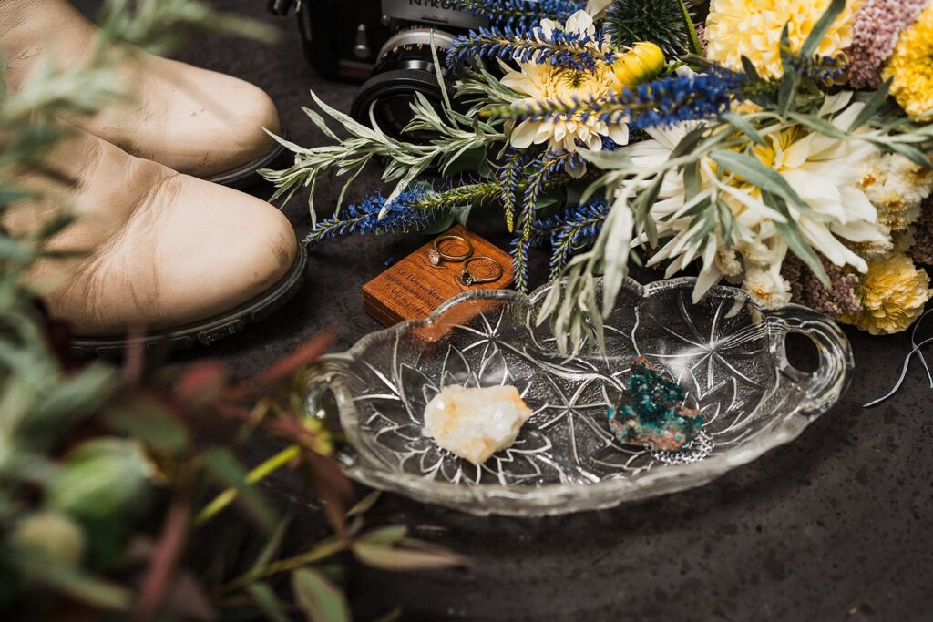 Crystals and wedding rings in a glass tray with elopement flowers