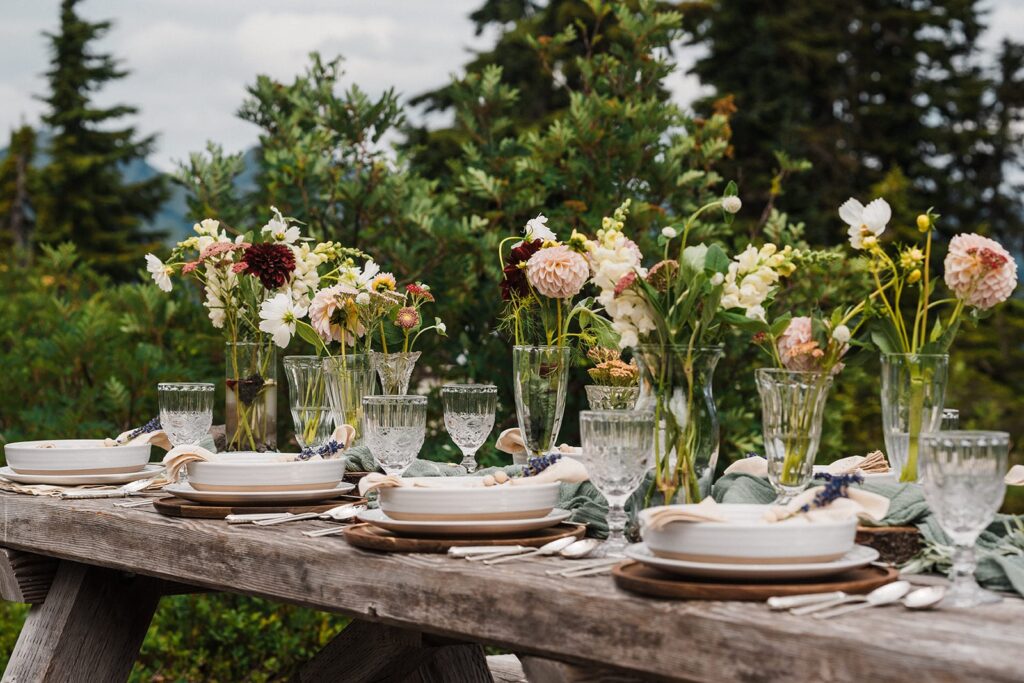 Light pink and burgundy flowers line a picnic table at a day use area in the North Cascades 