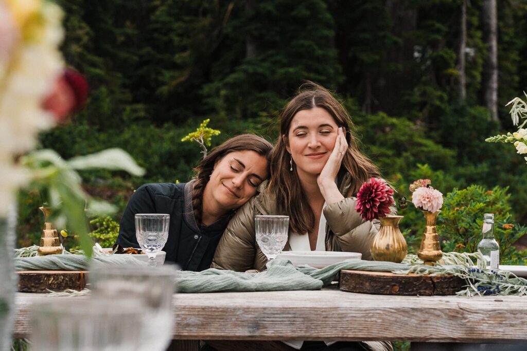 Brides lean against each other during their elopement picnic at a day use area in the North Cascades