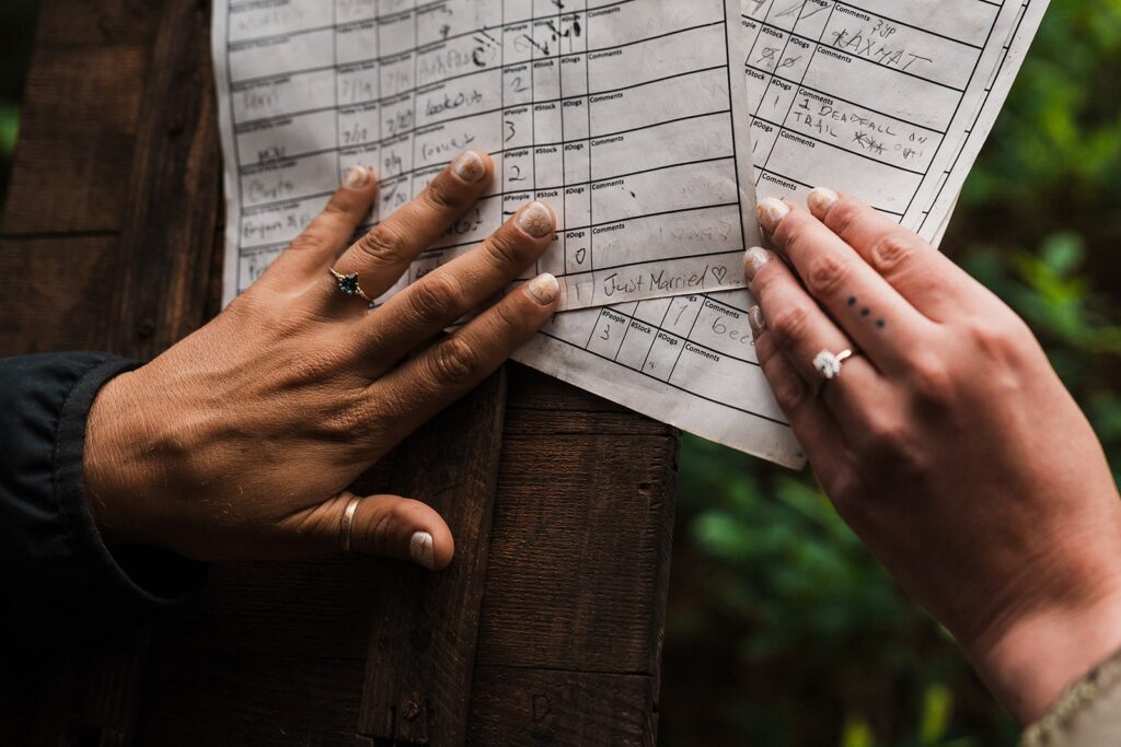 Brides fill out a trail log during their summer elopement in the North Cascades