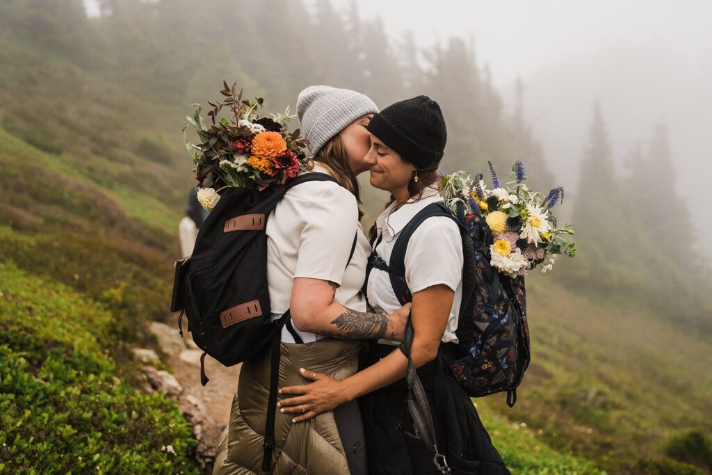 Brides kiss on a foggy trail during their summer elopement in the North Cascades