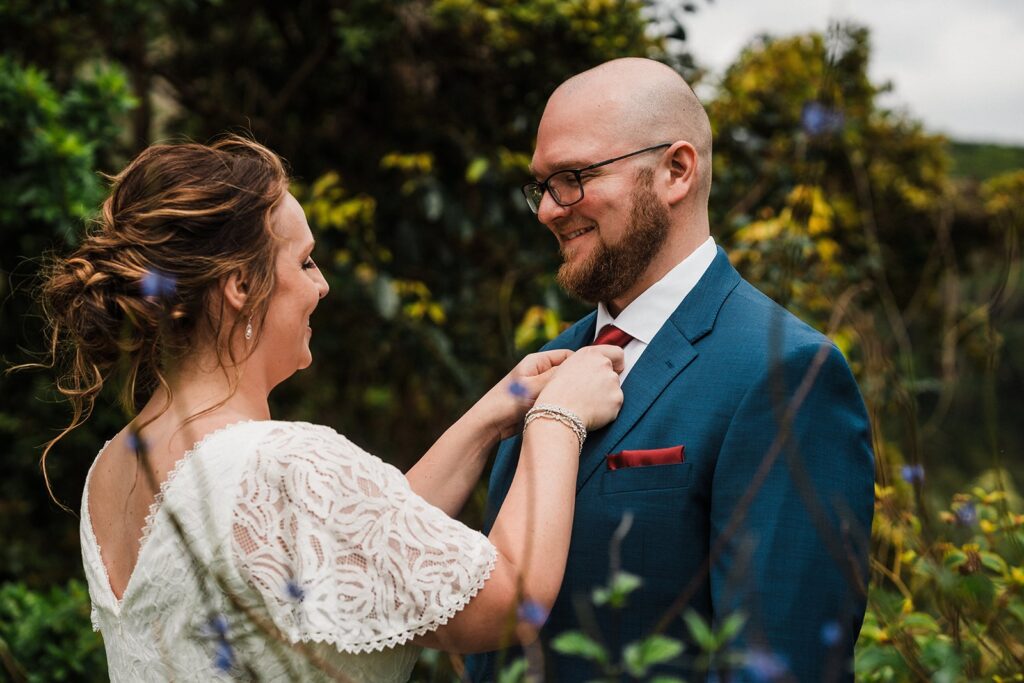 Bride adjusts groom's tie during their rainforest elopement in Kauai 