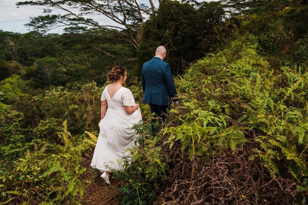 Bride and groom walk along a rainforest trail during their Kauai elopement 