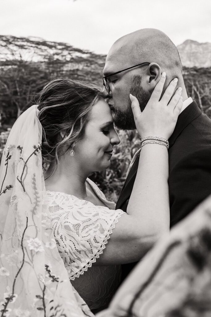 Groom kisses bride on the forehead during their elopement in Kauai 